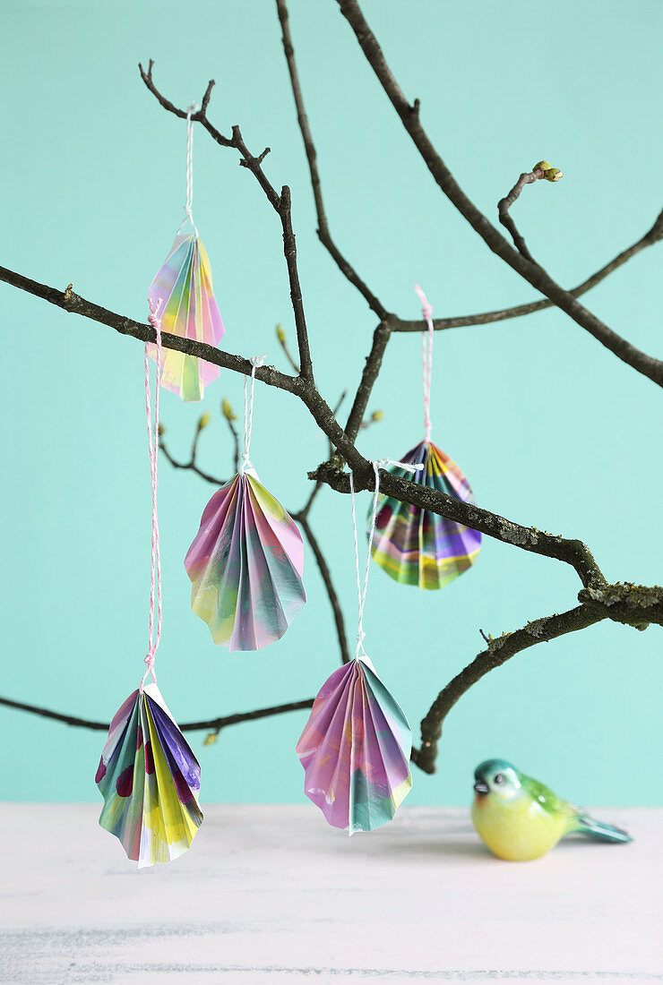 Folded paper Easter eggs hanging from branch