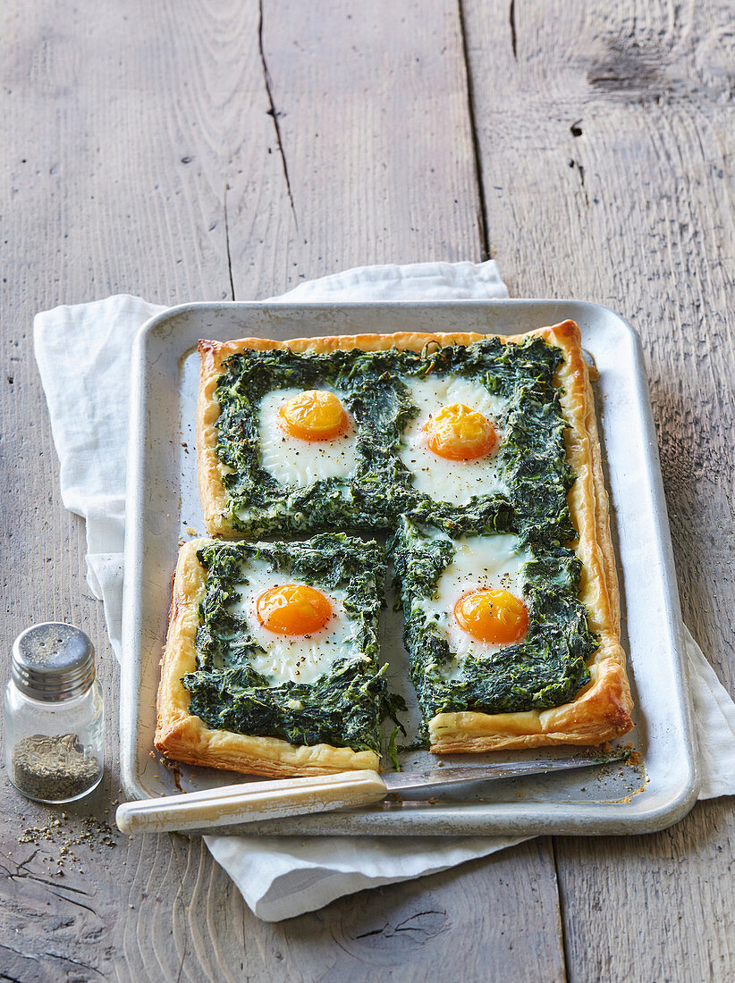 Puff pastry cake with spinach and fried eggs