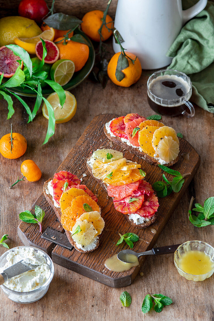 Brote mit Frischkäse, gemischten Zitrusfrüchten und  Honig