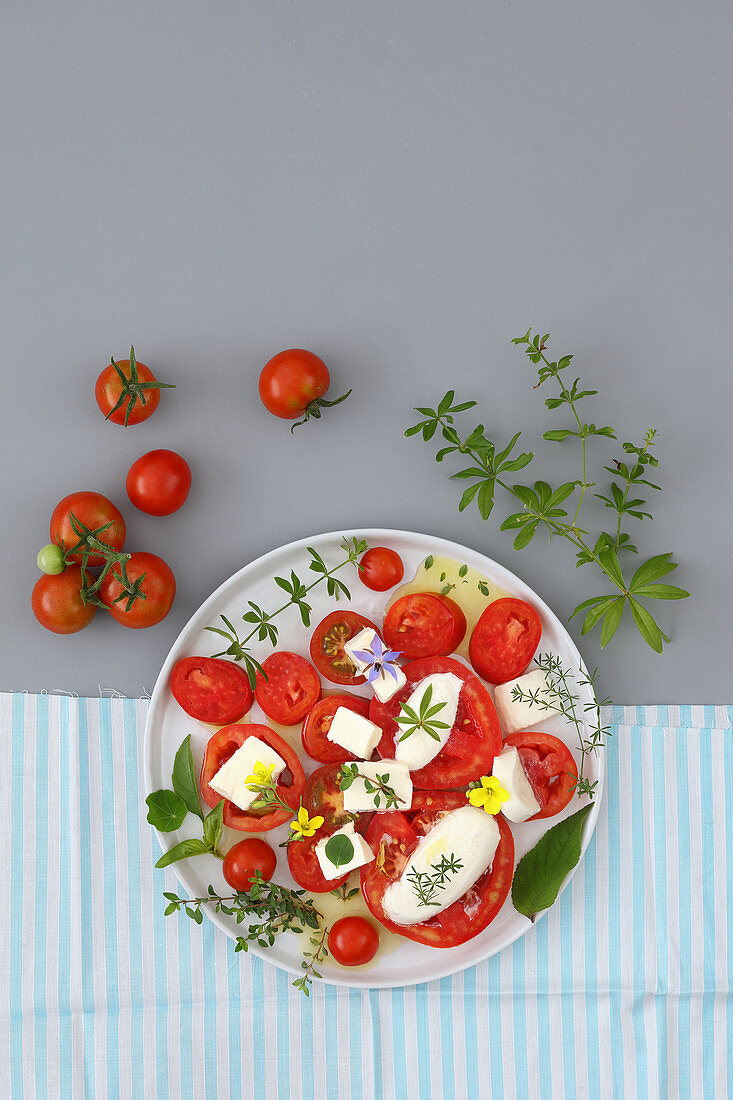 Mozzarella and tomatoes salad with herbs and edible flowers
