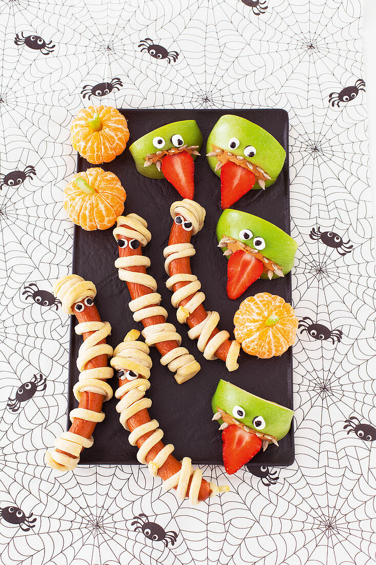 Halloween Snack-Partybuffet mit Würstchen-Mumien und Appleheads