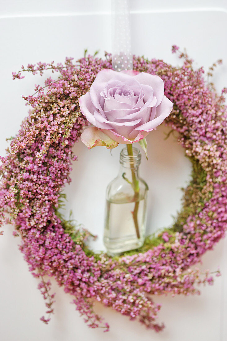 Heather wreath with rose in small bottle decorating door
