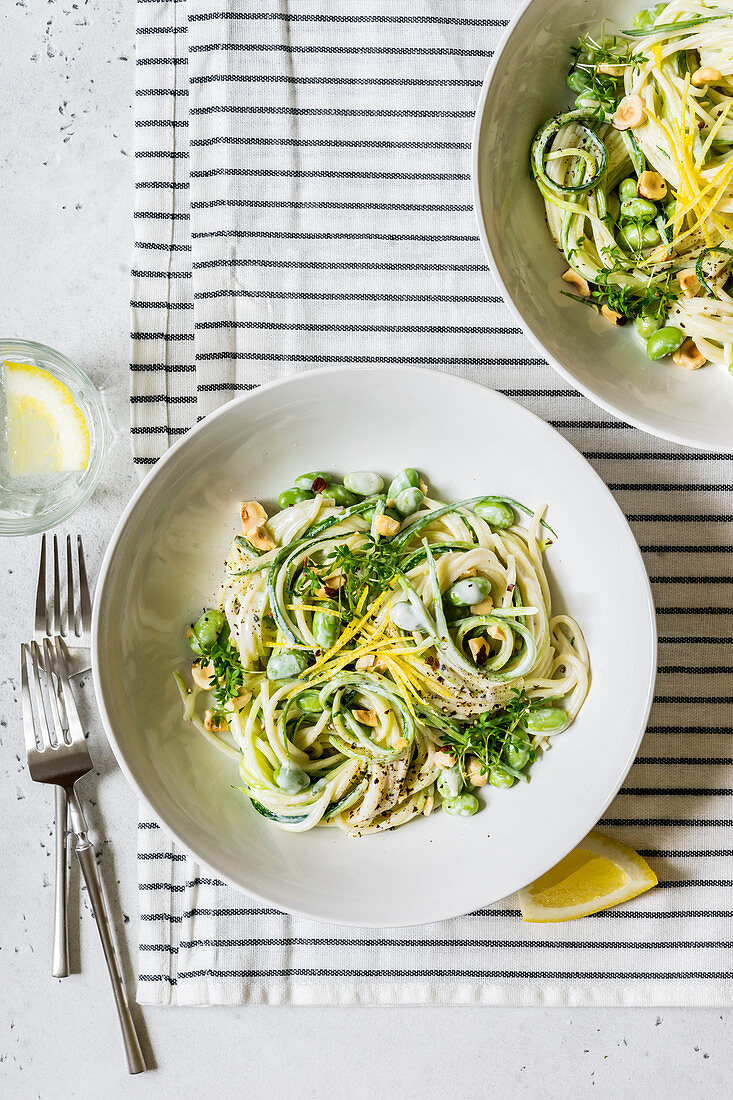 Light Vegetarian Creamy Spagetti Pasta with Zucchini Strips, Edamame Beans, Lemon Zest, Walnuts and Cress Microgreens