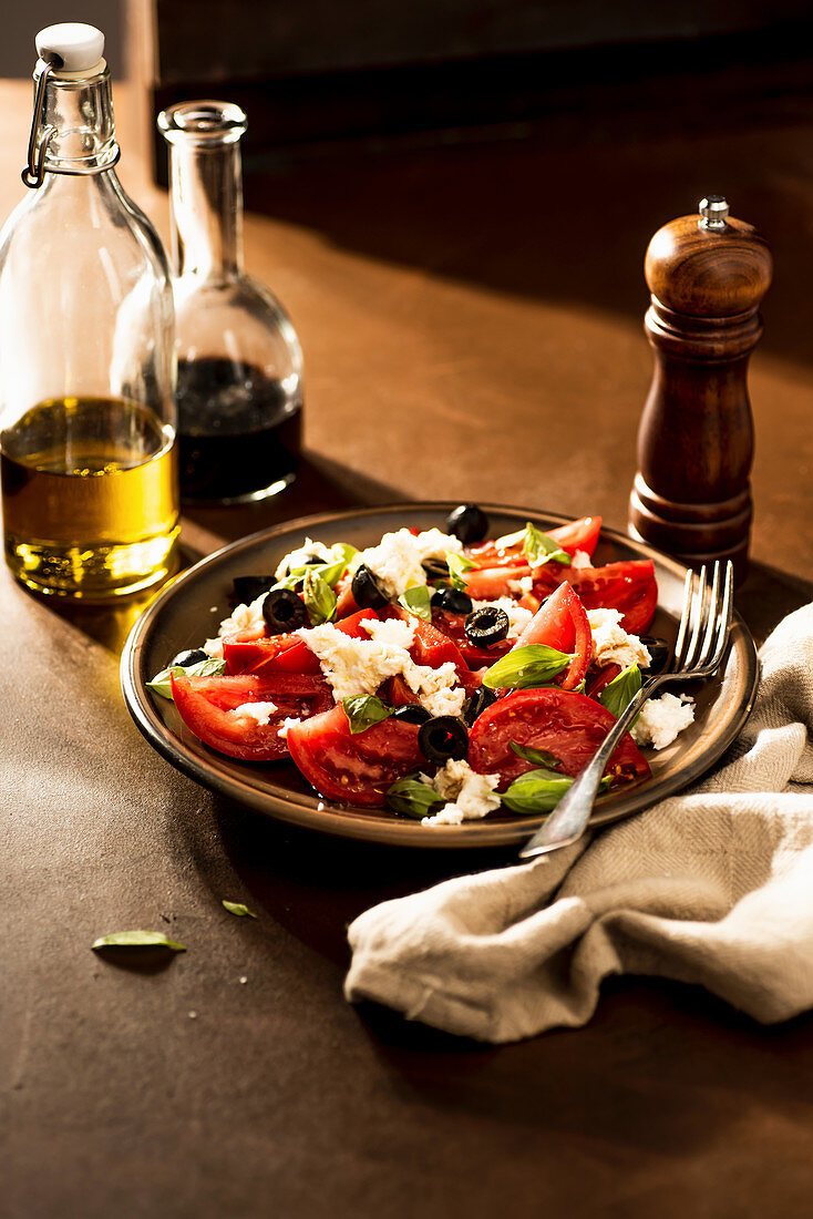 Tomatensalat mit schwarzen Oliven, Mozzarella und Basilikum
