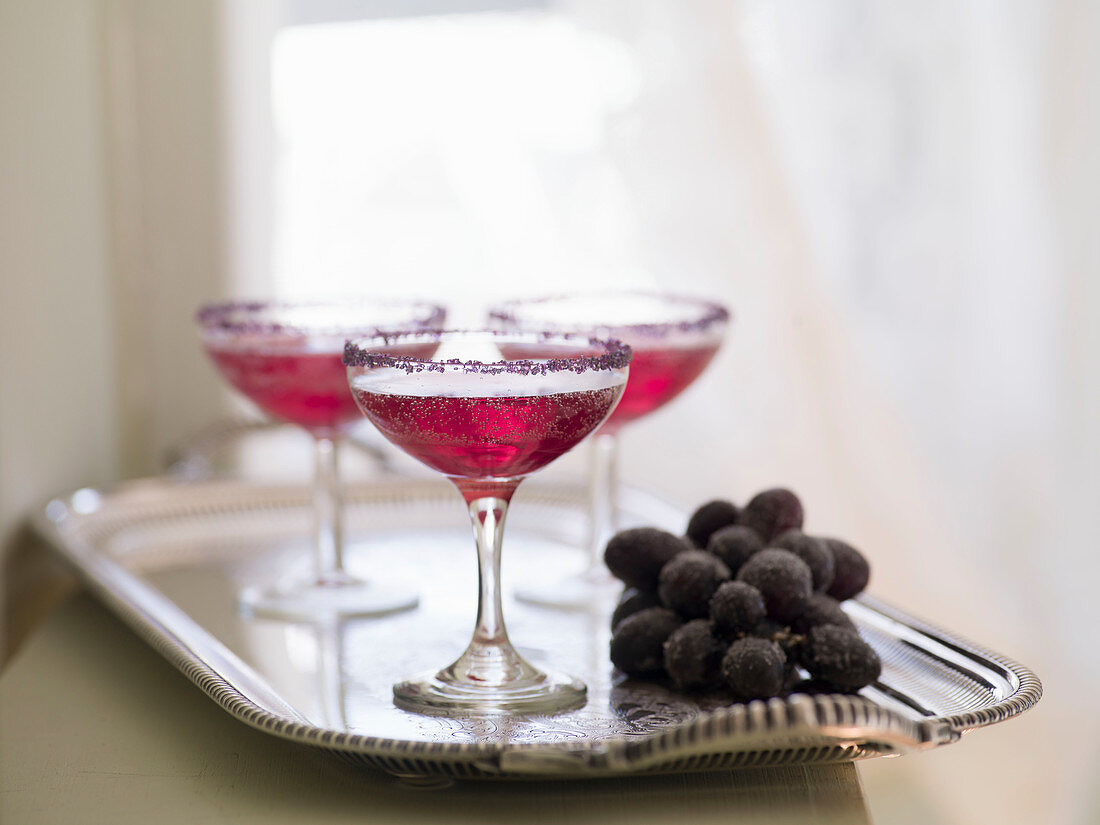 Rote Cocktails mit gezuckerten Trauben auf einem Silbertablett