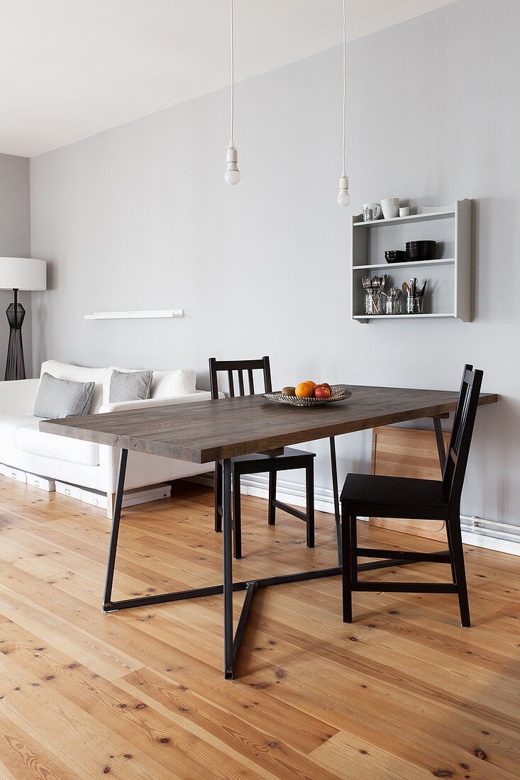 Dining table with dark wooden top and black chairs in open-plan interior