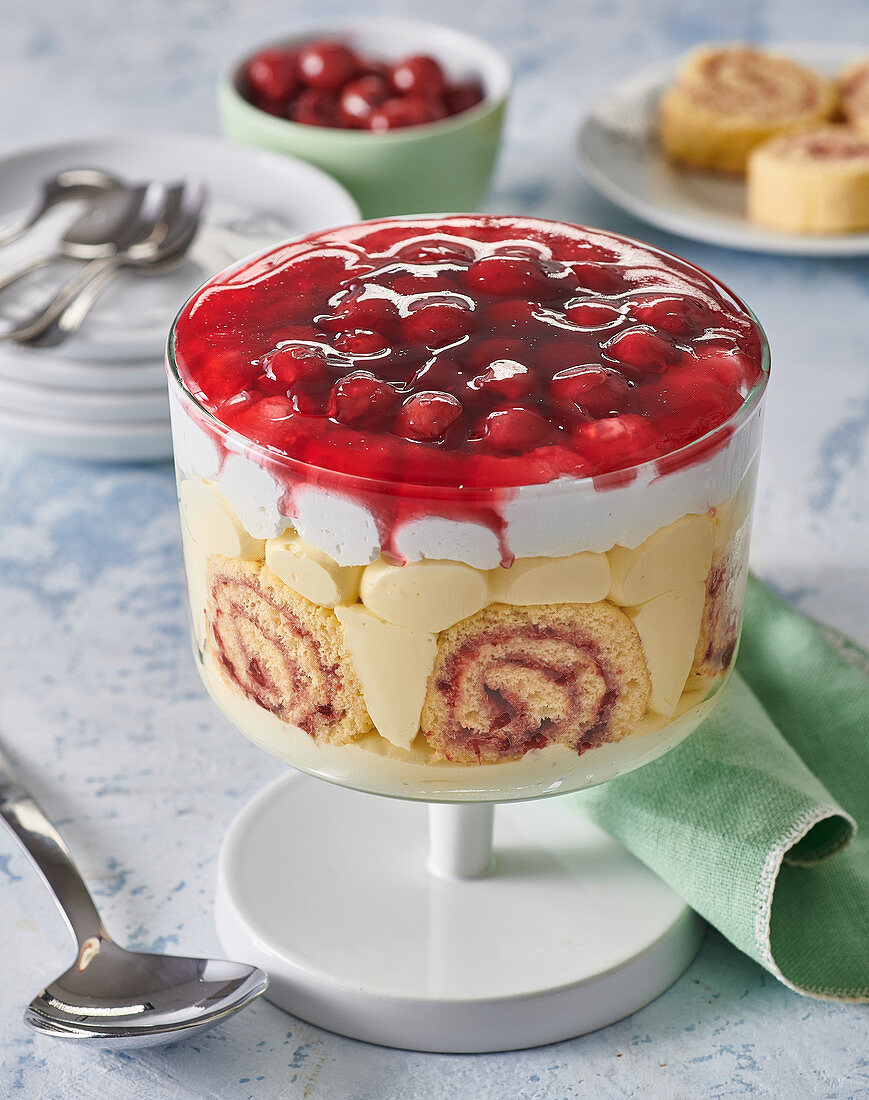 Trifle mit Biskuitröllchen, Sahne und Kirschen