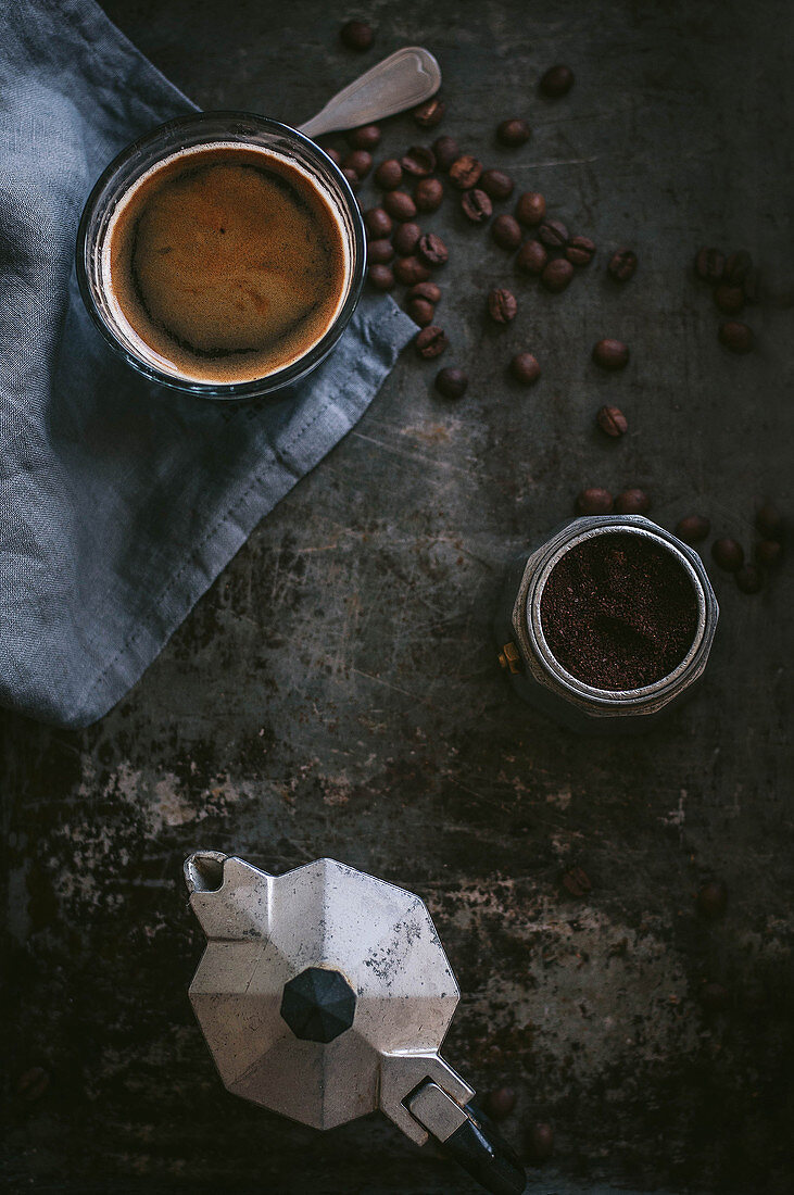 Stillleben mit Espresso, Kaffeebohnen, Kaffeepulver und Espressokanne