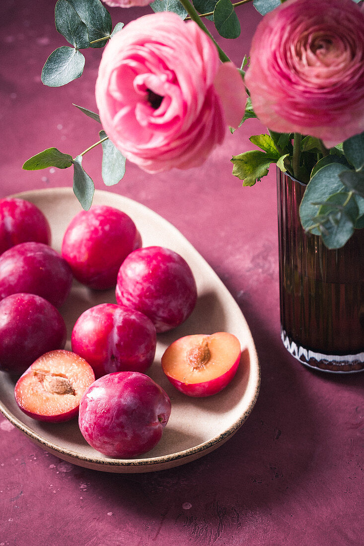Plums on the plate and ranunculus