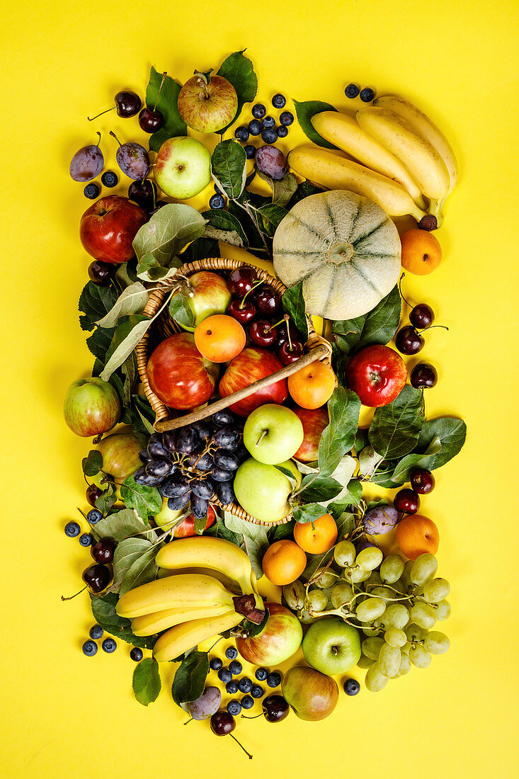 Fresh fruits and berries on yellow background