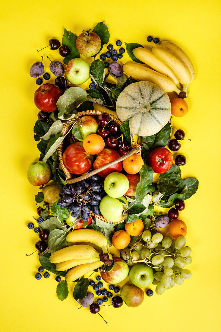 Frische Früchte und Beeren auf gelbem Untergrund