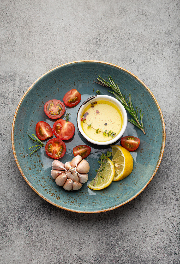 Gemüse, Kräuter, Gewürze und Olivenöl in blauem Keramikteller