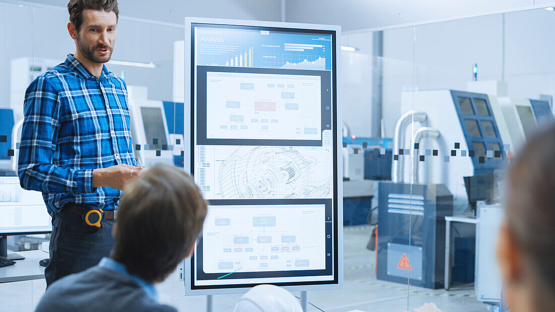 Engineer using a digital whiteboard in a factory meeting