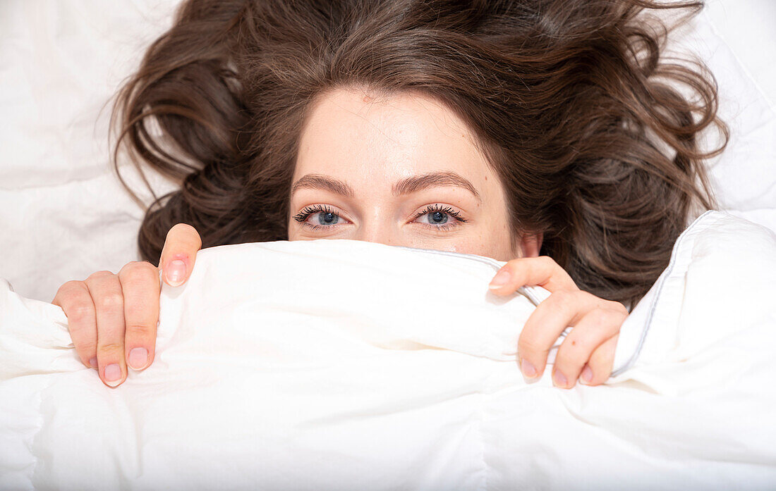 Woman hiding under blanket