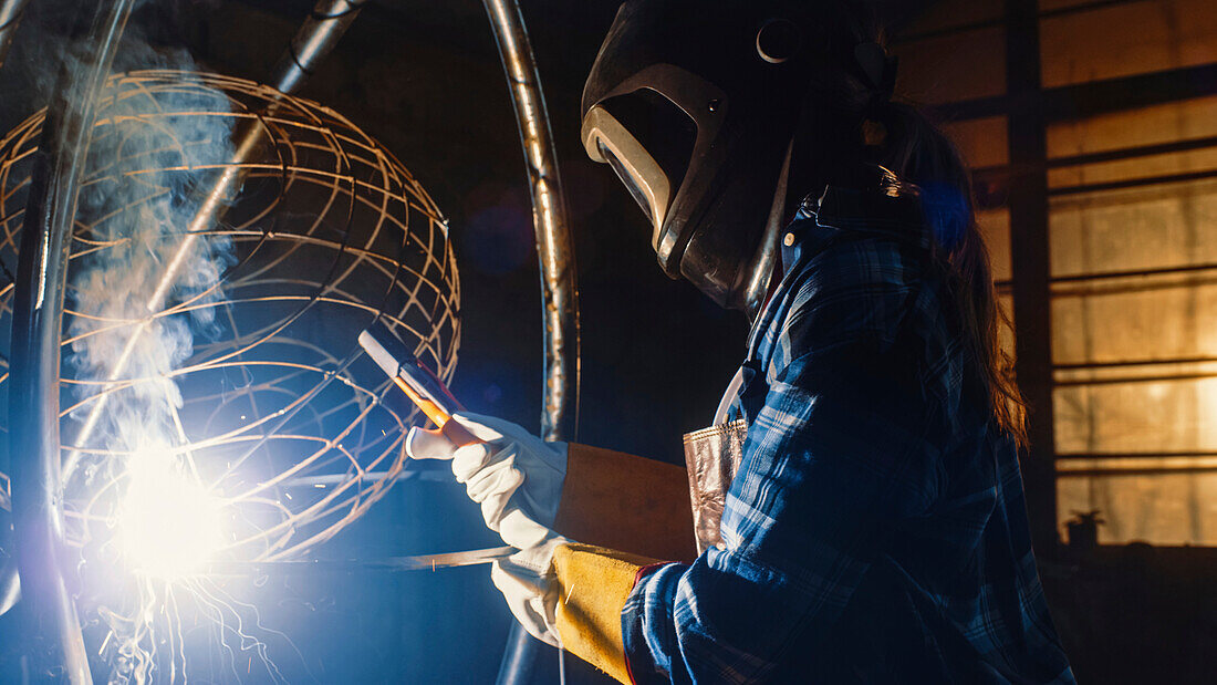 Sculptor welding an abstract metal sculpture