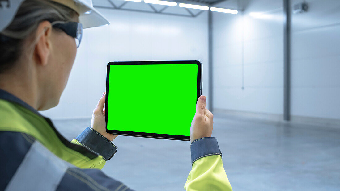 Engineer using a tablet with a green screen