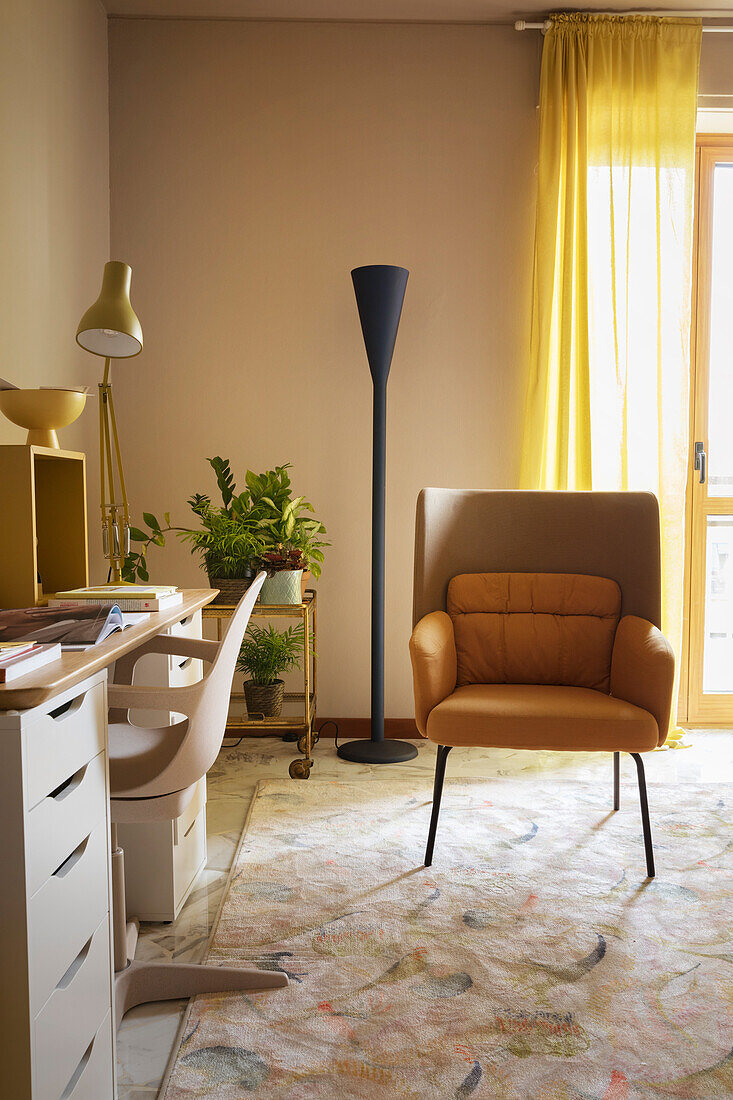 Desk and armchair in living room with yellow curtain