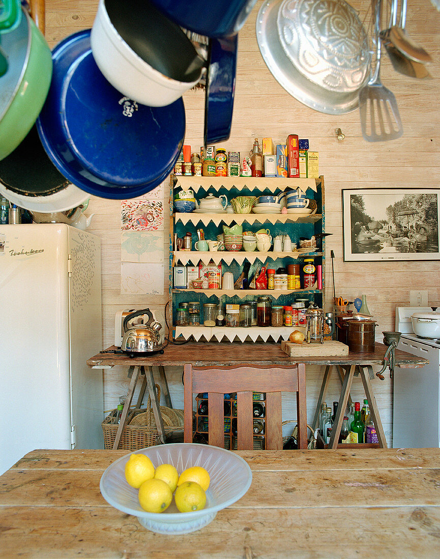 Pans hanging over kitchen table with shelved in background