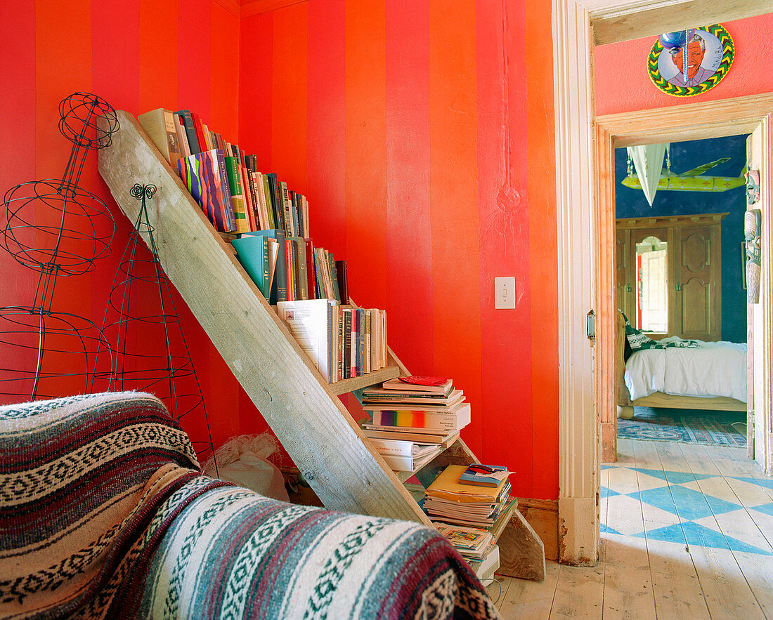 Old ladder used as bookshelves in room with red walls