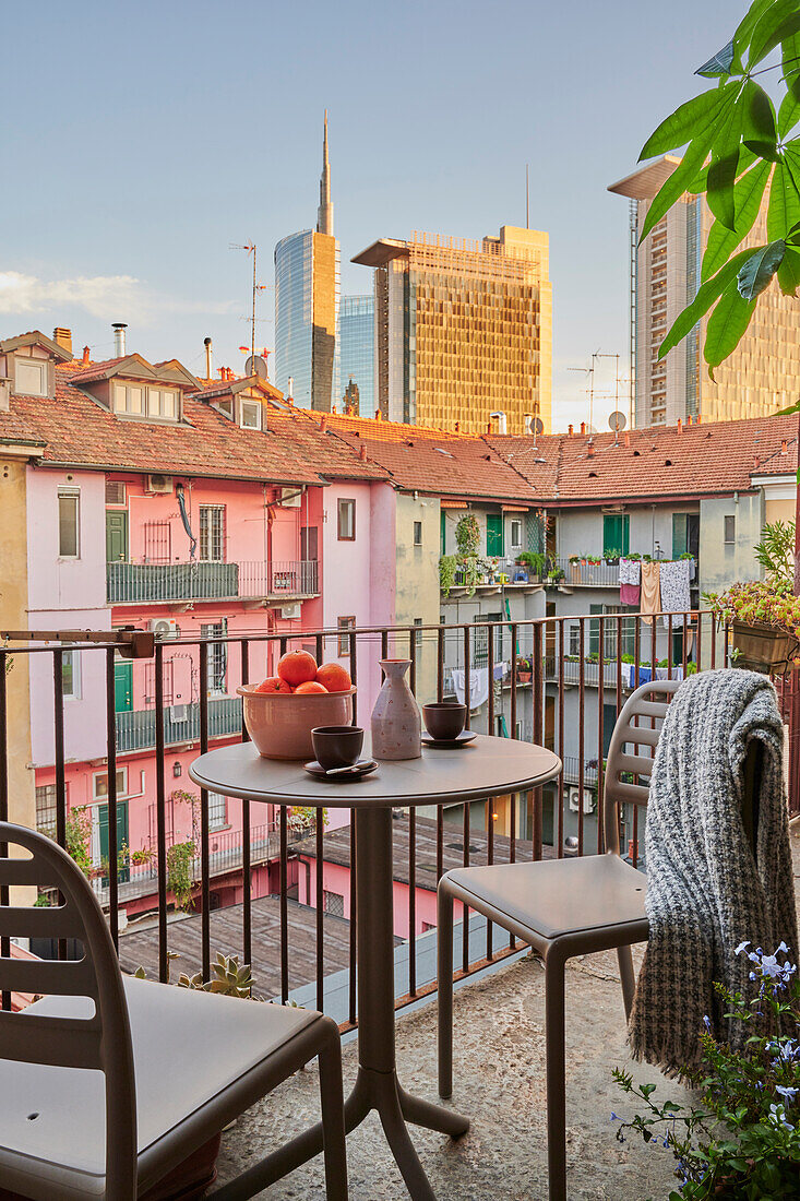 Bistrotisch mit zwei Stühlen auf Balkon, Blick auf Nachbarsgebäude