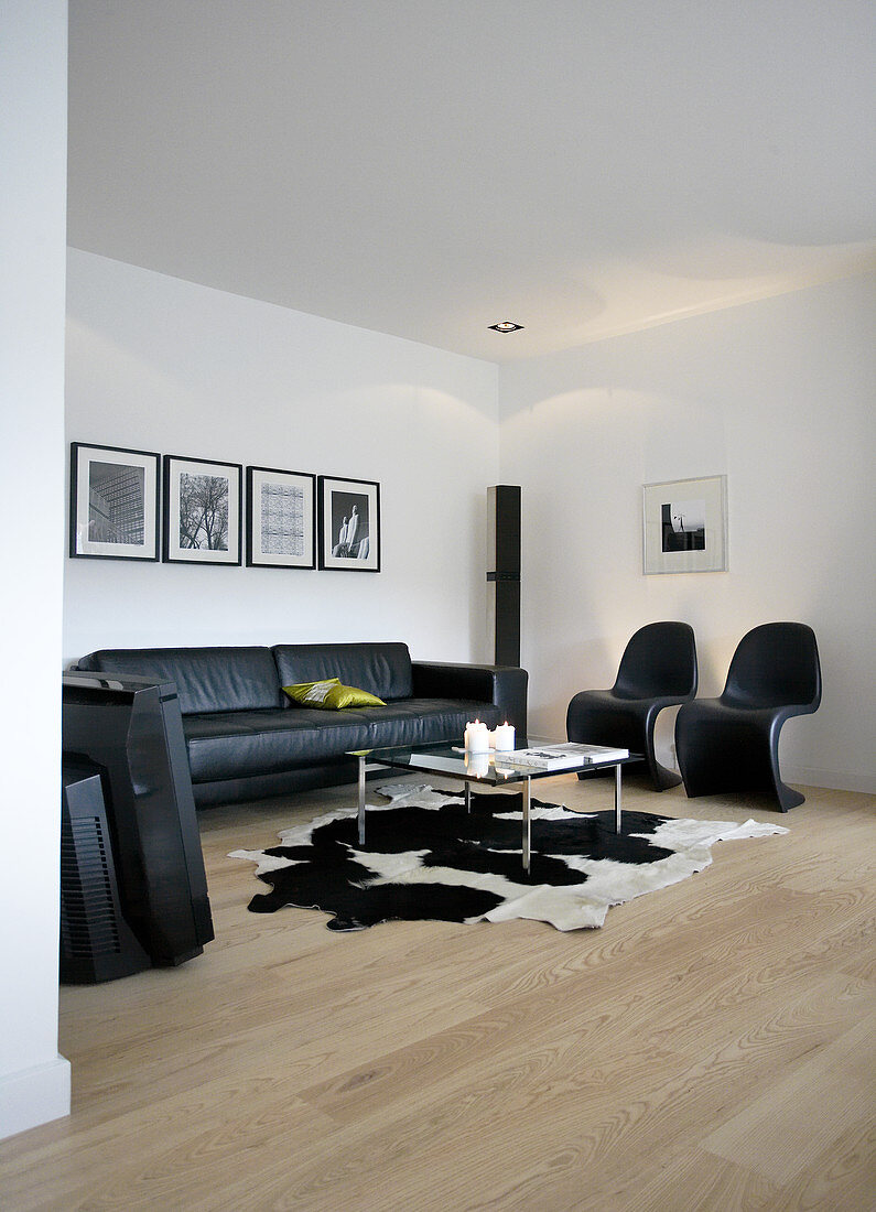 Black classic chairs, leather sofa and coffee table on cowhide rug in living room