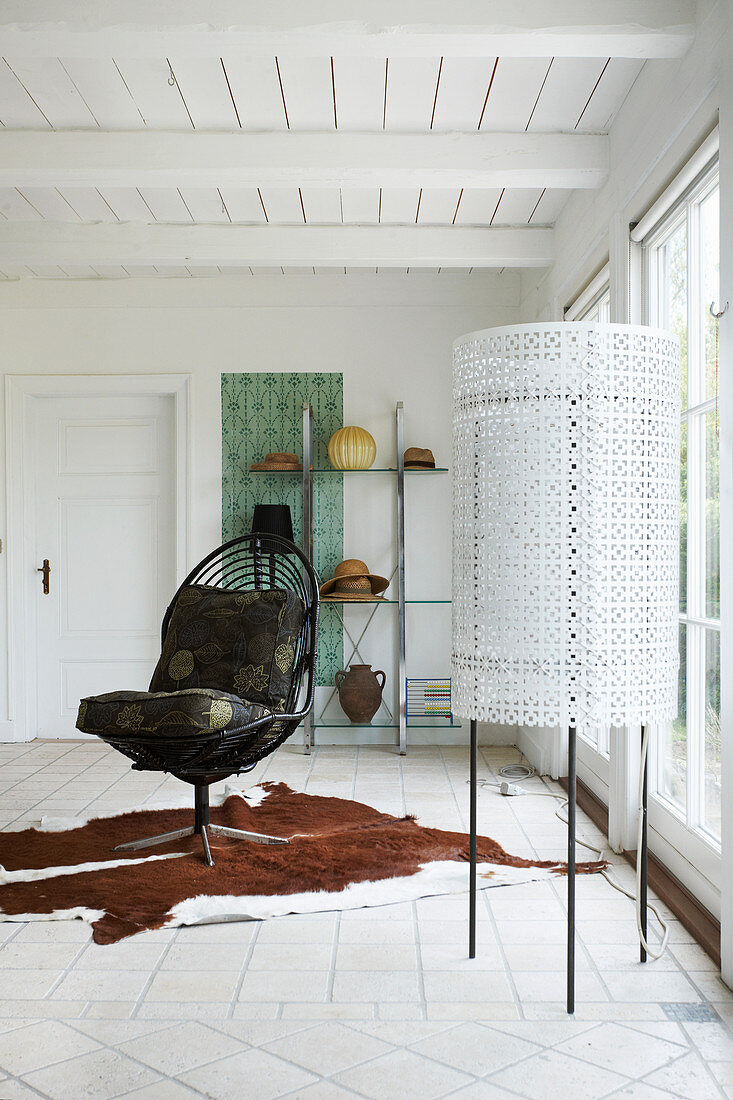 Black chair on cowhide rug and standard lamp next to terrace doors