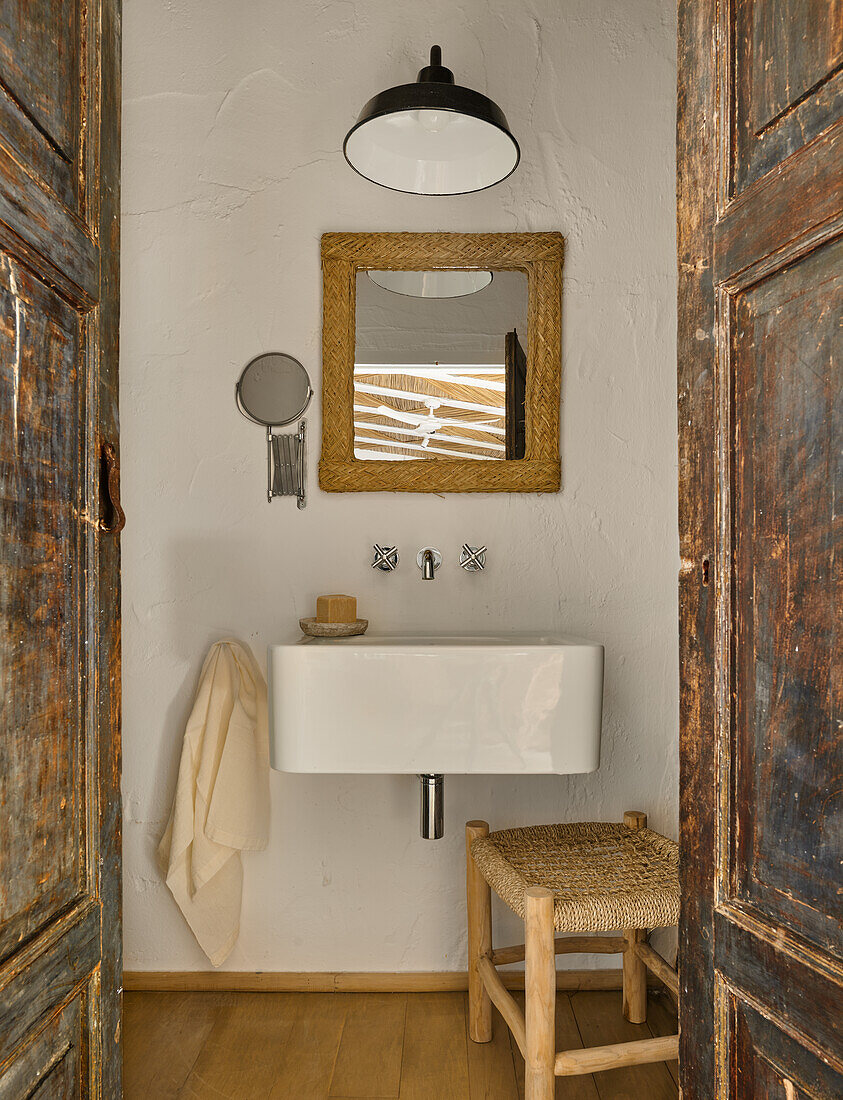 View through open wooden doors towards the bathroom sink