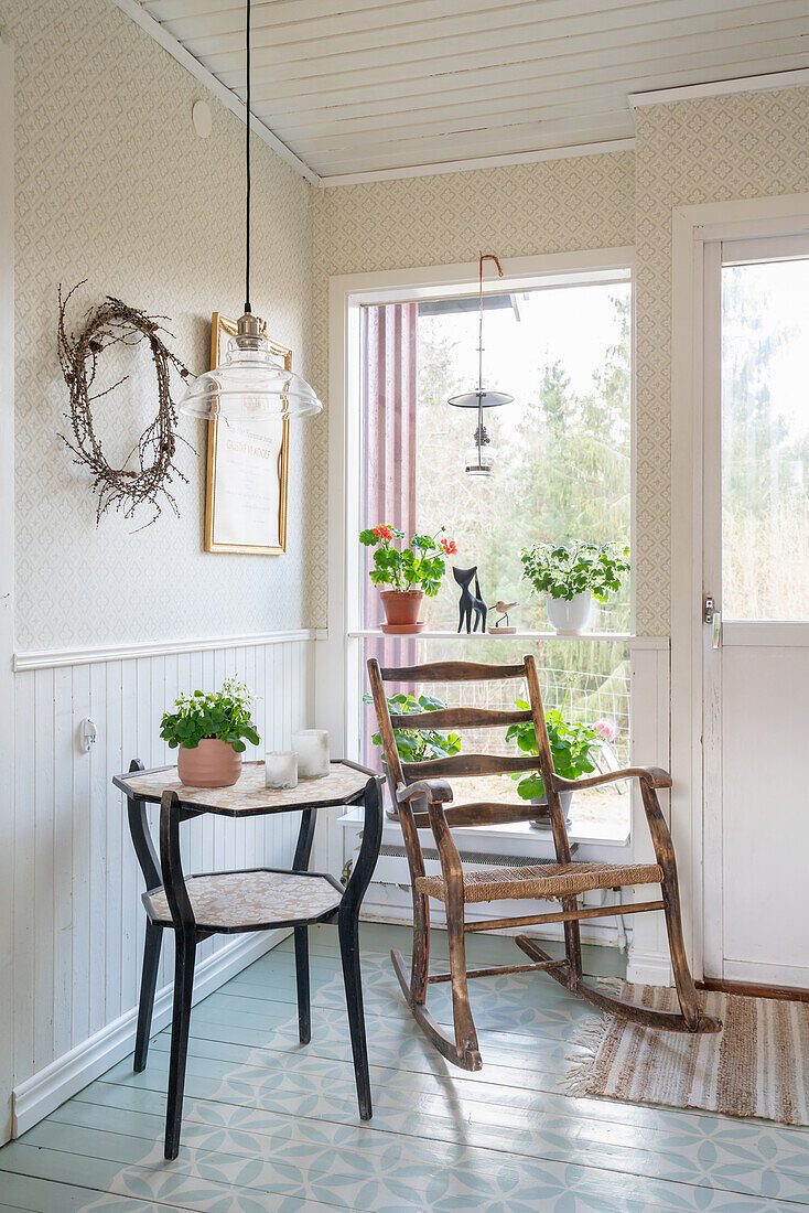 Old rocking chair and side table in front of a window