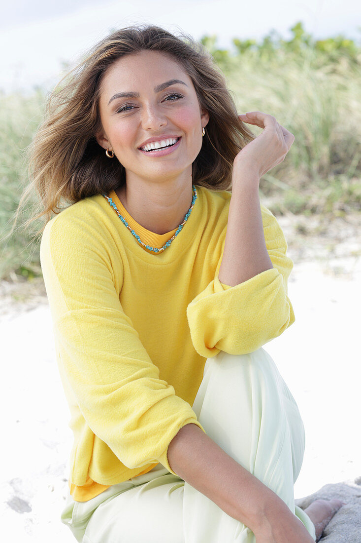 A young woman with long hair wearing a yellow jumper and trousers