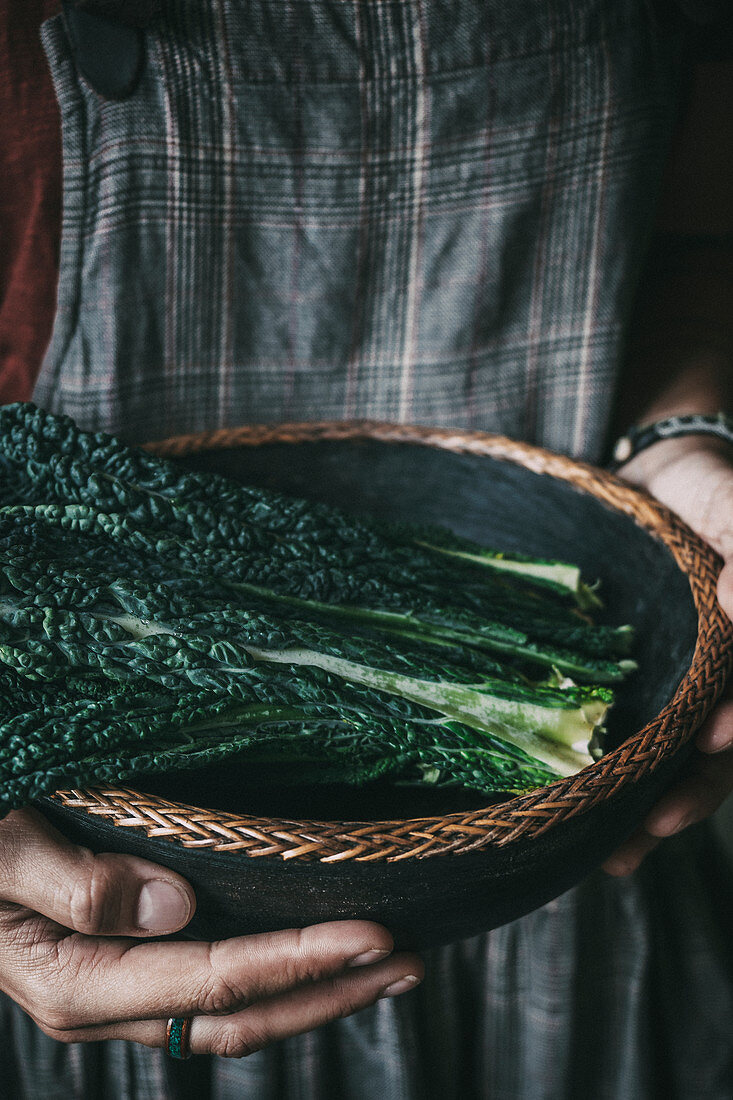Person holding bowl with kale leaves