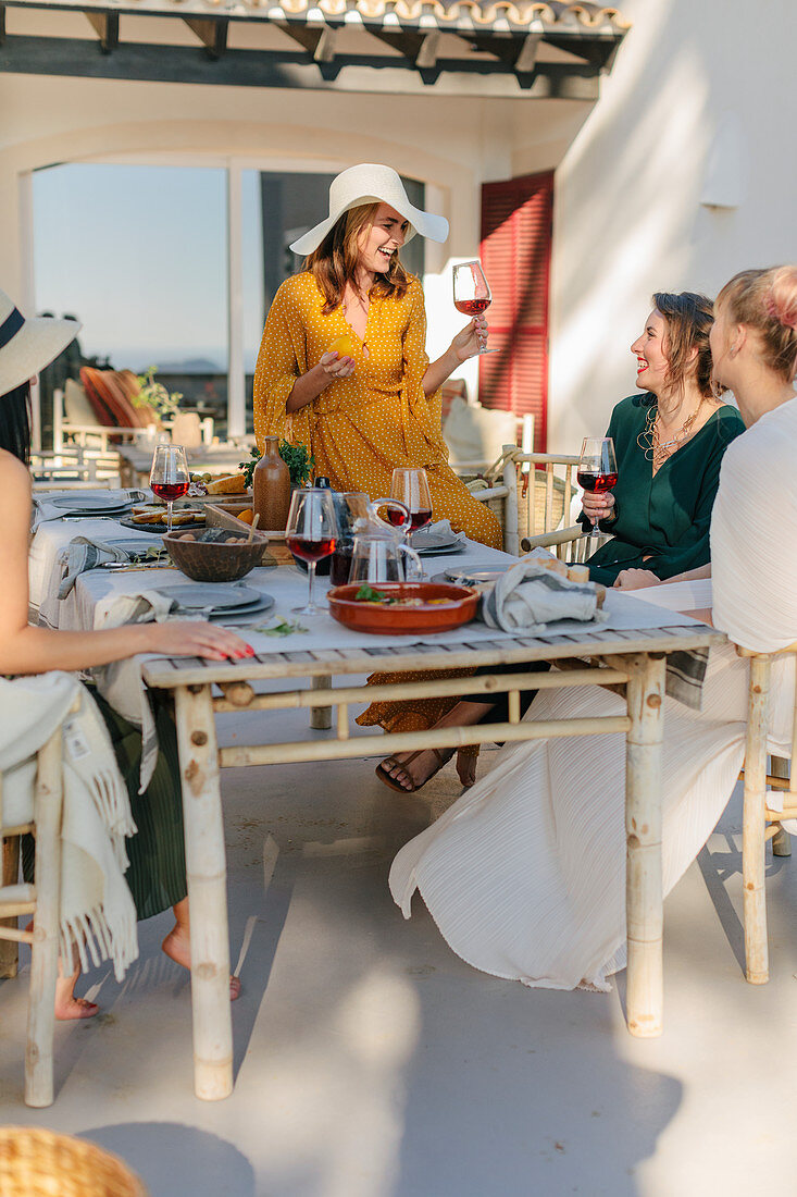 Fröhliche Frauen am Esstisch auf Terrasse