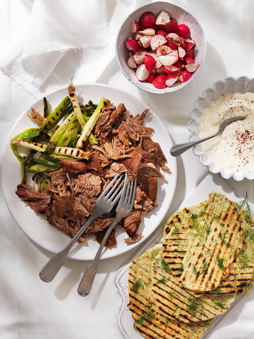 Shawarma spiced lamb shoulder, spring onions, radishes and herby flatbreads