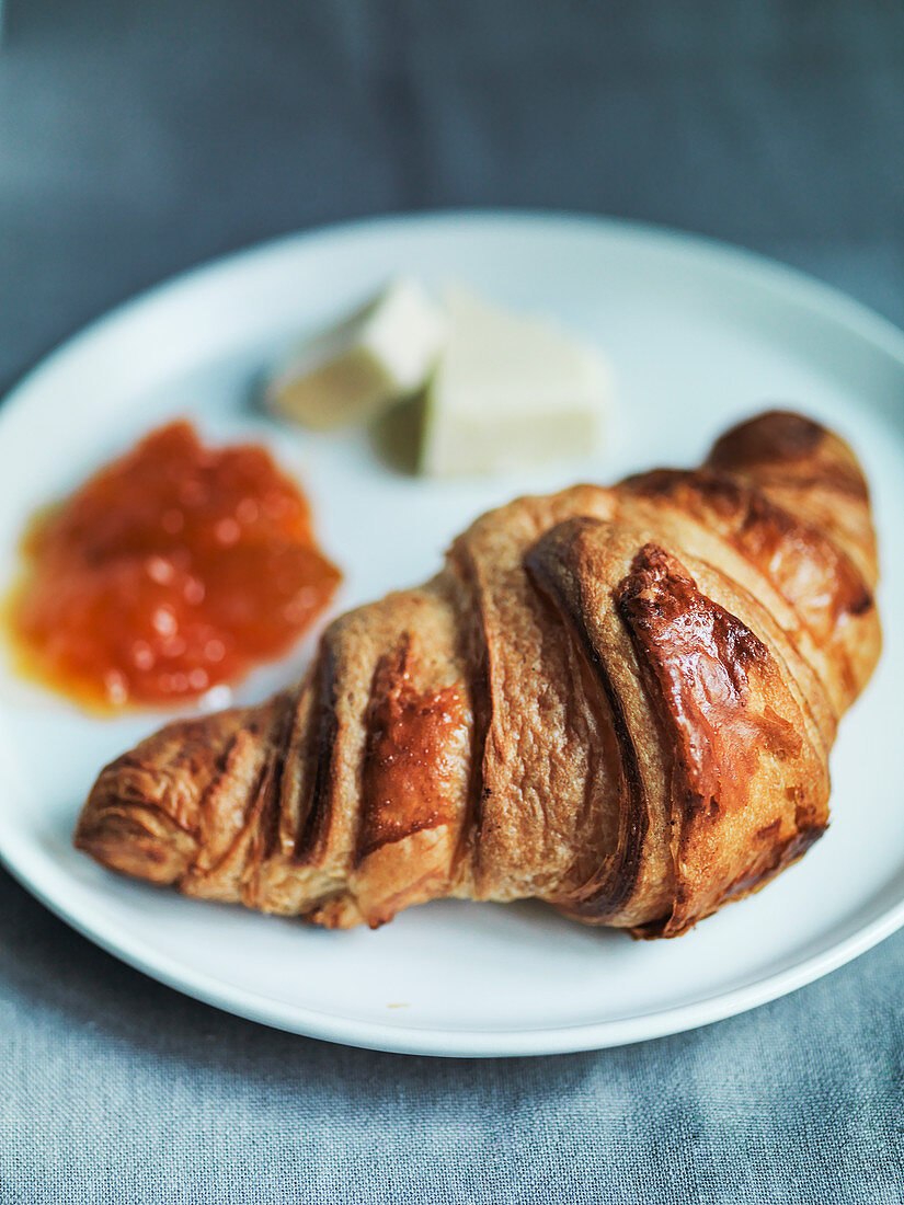 Fresh baked Croissant with apricot jam and butter