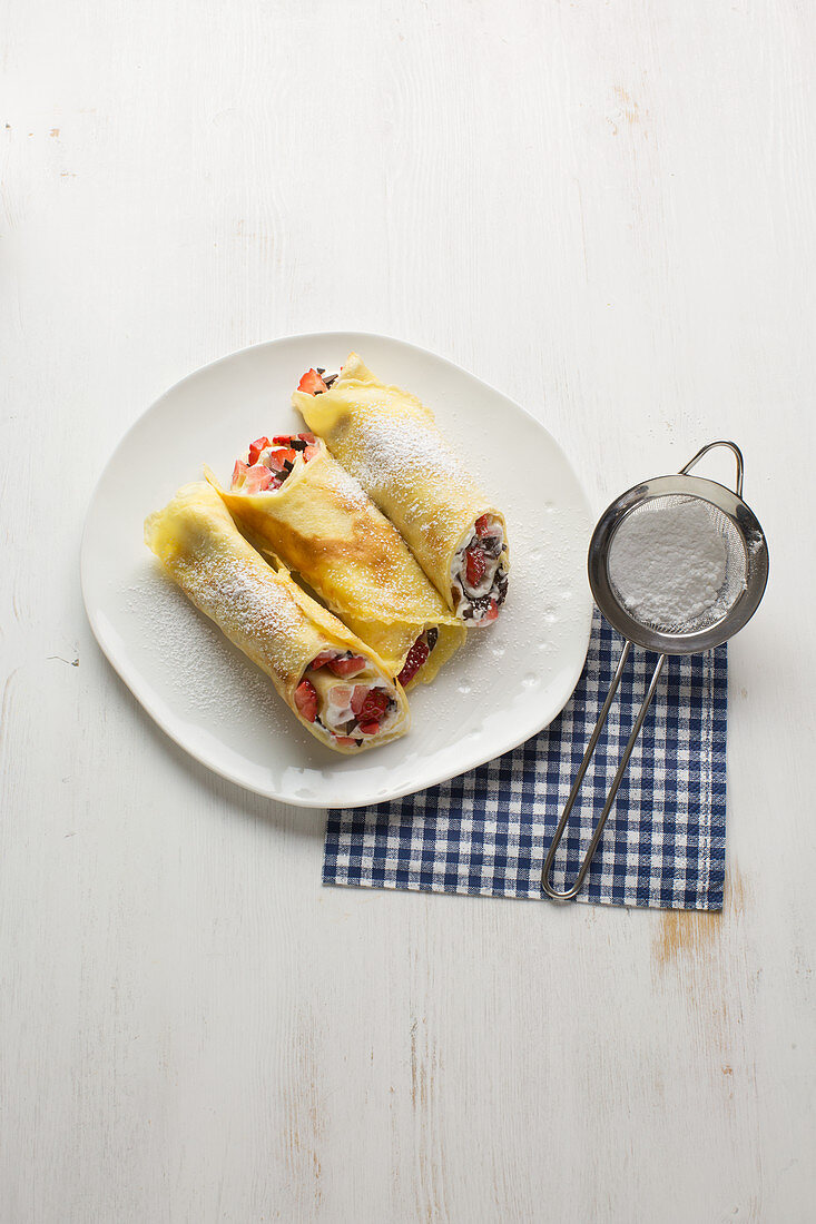 Pancake rolls with yogurt, strawberries and grated chocolate