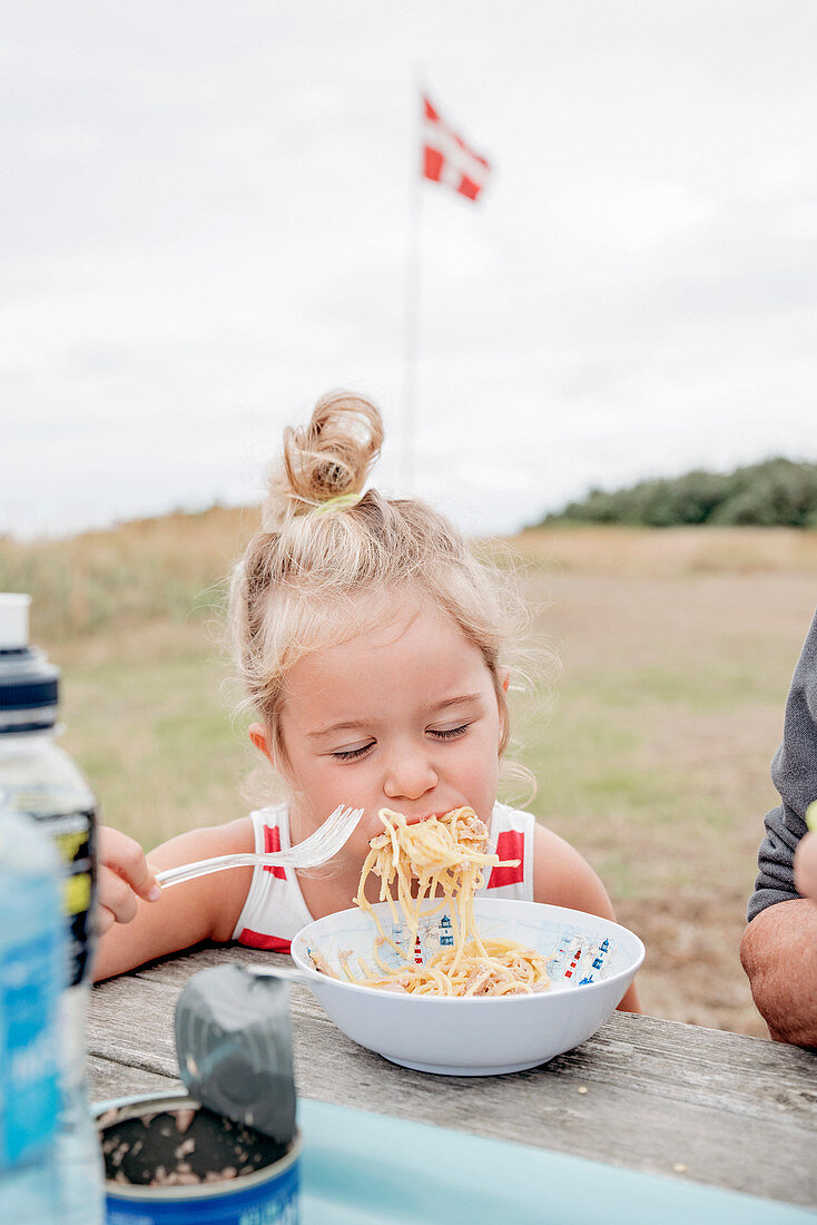 Girl eating spaghetti outside