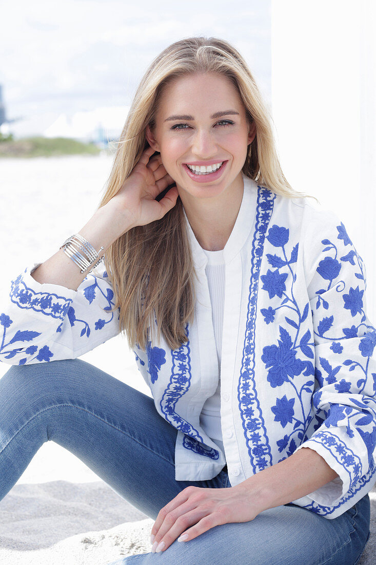 A long-haired blonde woman wearing jeans and a blue-and-white jacket