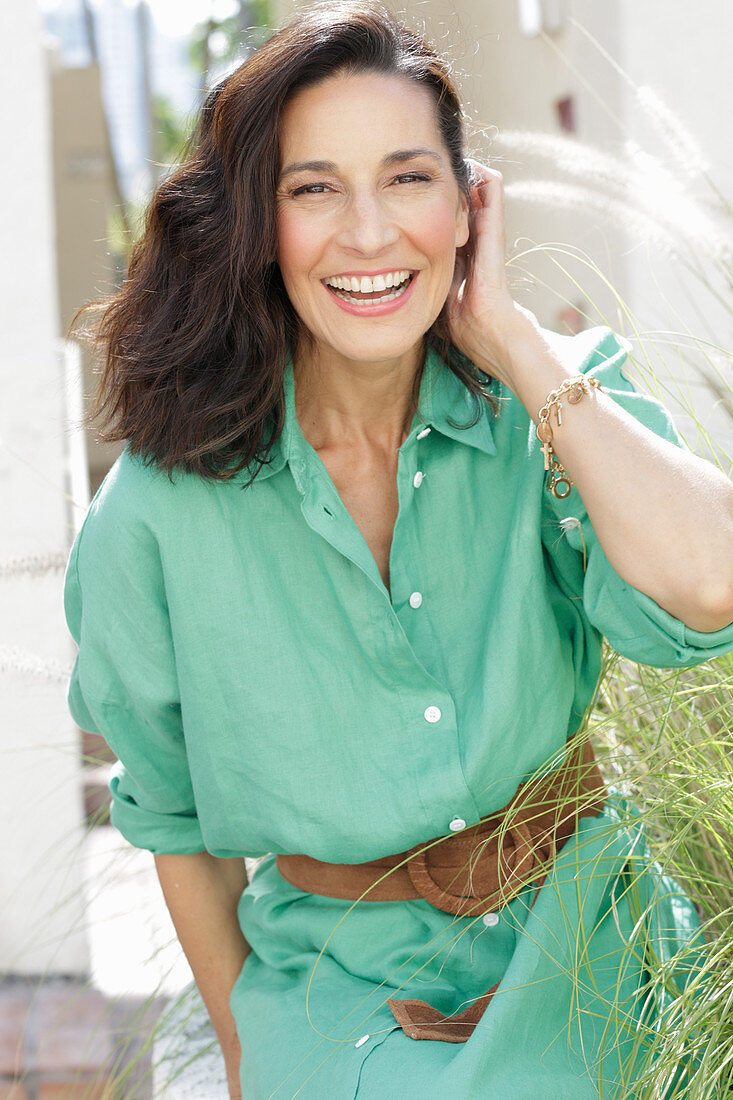 An older brunette woman wearing a green dress