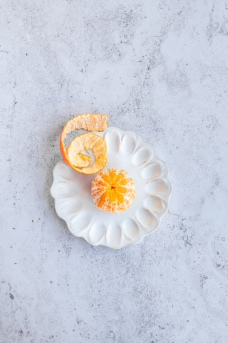 Peeled honey gold tangerine on a decorative ceramic plate