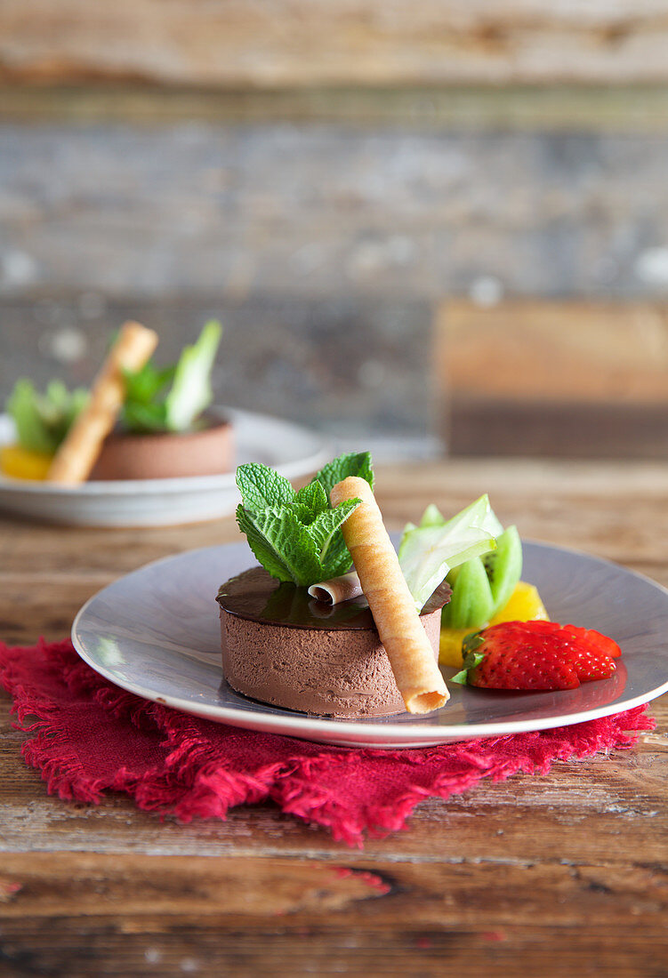 Thai chocolate dessert with fruit garnish and rolled wafers