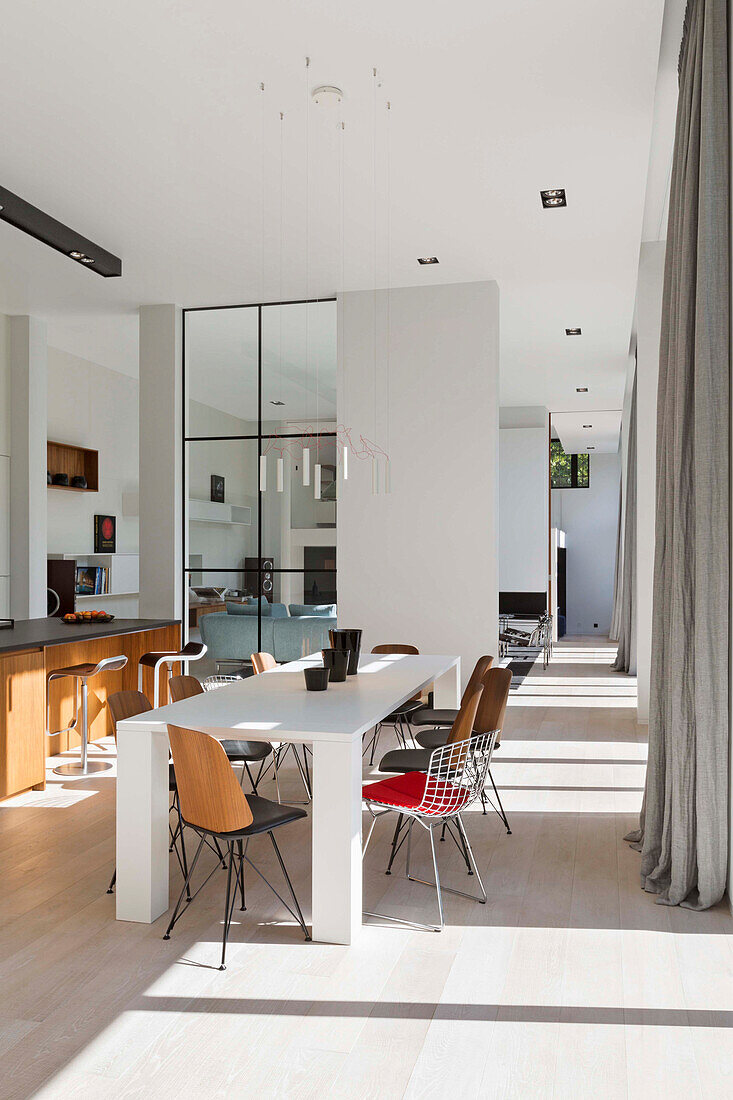 White dining table with various chairs in an open living room