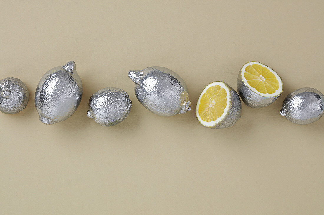 Silver painted yellow lemons for decor table of beige background