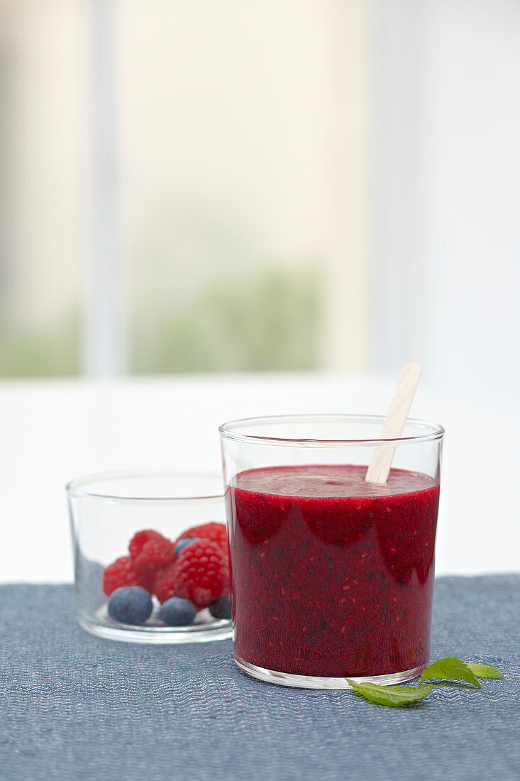 Strawberry and black current smoothie near luminous window inside Tupperware