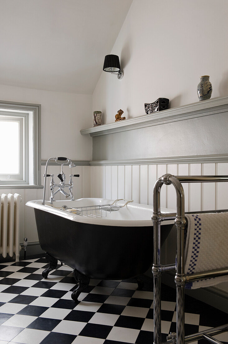 Schwarze, freistehende Badewanne im Badezimmer mit schwarz-weiß kariertem Boden