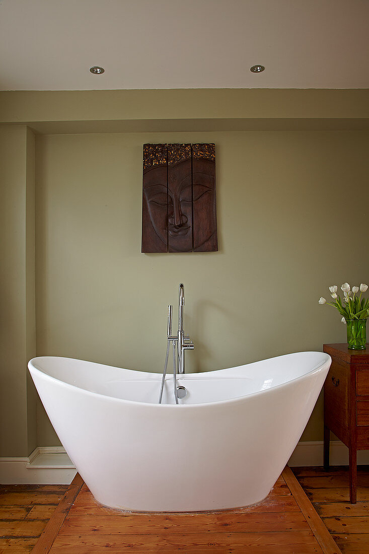 Free-standing bathtub in the bathroom with an olive green wall