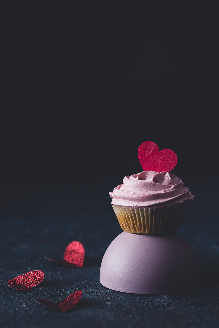 Cupcake mit rosa Frosting und Herzdekoration zum Valentinstag
