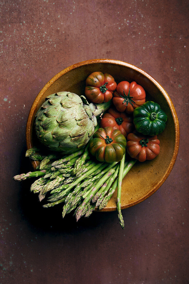 Tomatoes, artichokes and asparagus in a stoneware bowl