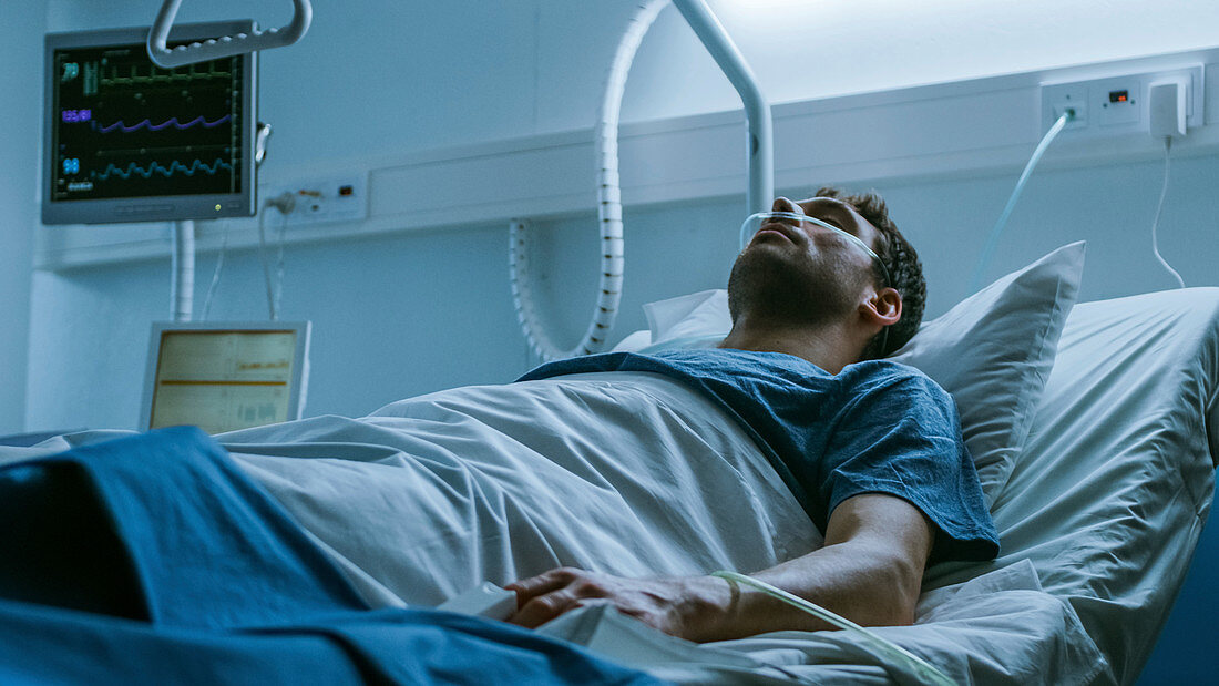 Ill man suffering while lying in a hospital bed