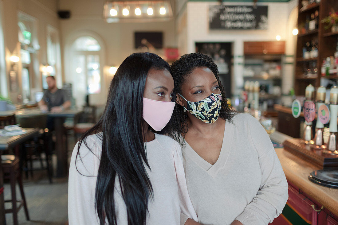 Mother and daughter in face masks in a pub