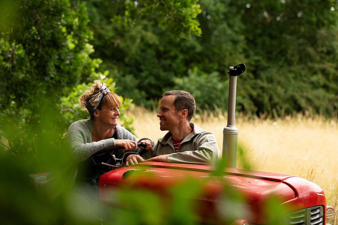 Happy couple talking at tractor in orchard