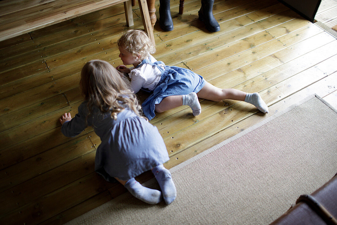 Sisters crawling on hardwood floor